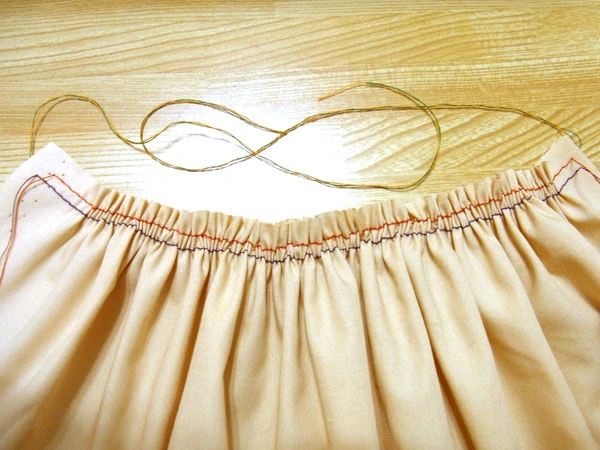 Evenly pulling bobbin threads from both sides to form gathers